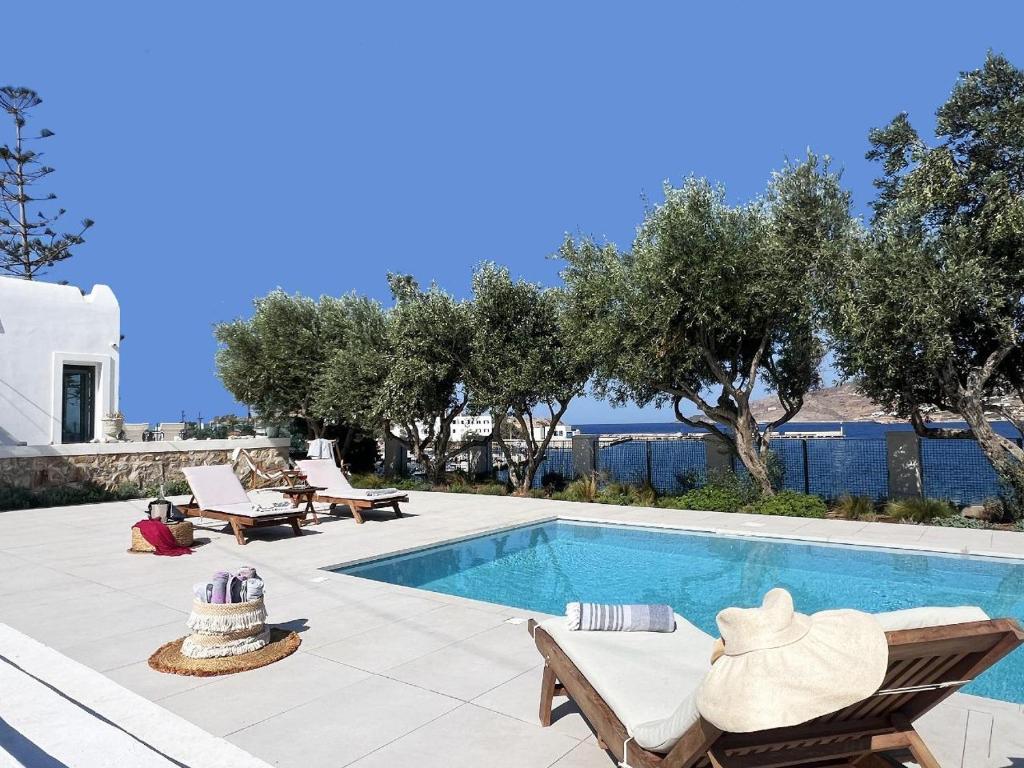 a swimming pool with chairs and a table and a house at Sunset Villa in Posidhonía