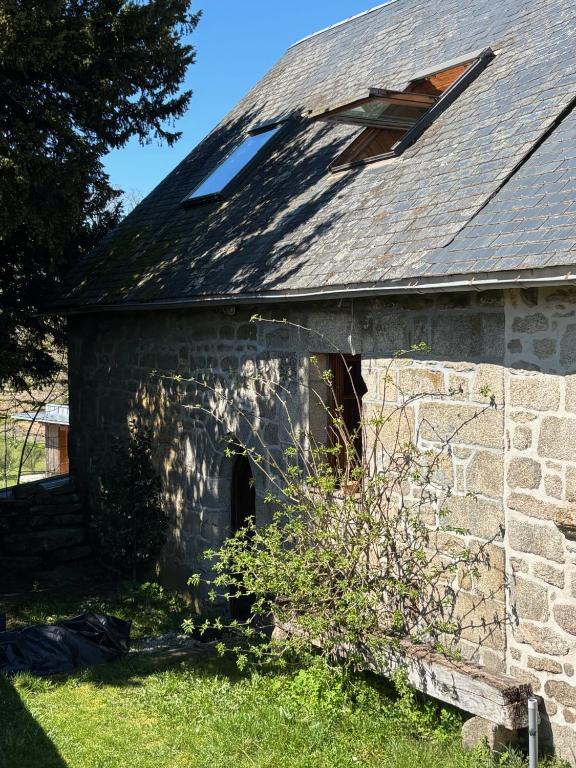 an old stone building with a shingled roof at La maison de Baptiste La Monédière in Chaumeil