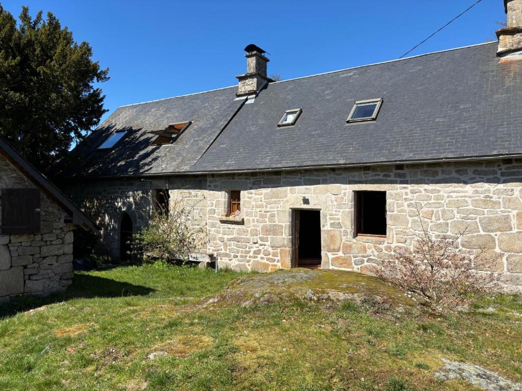 an old stone building with a black roof at La maison de Jeanne La Monédière in Chaumeil