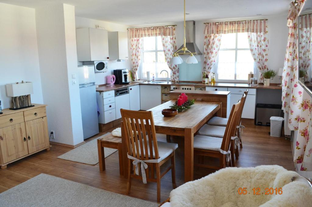 uma cozinha com mesa e cadeiras de madeira e uma cozinha com armários brancos em Die Dirndlkönigin em Grünenbach
