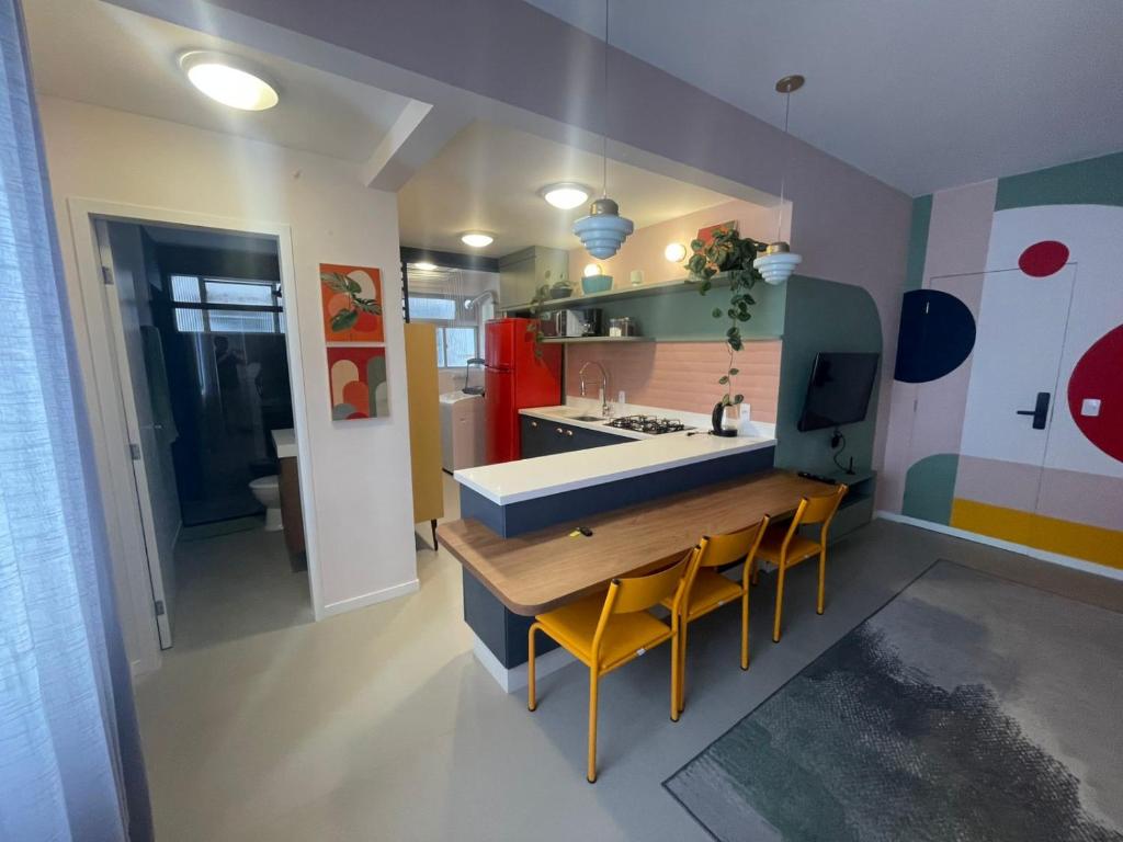 a kitchen with a wooden table and yellow chairs at Incrível apto com banheira e garagem perto de tudo in Florianópolis