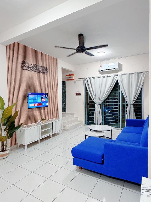 a living room with a blue couch and a tv at EQAMEL Homestay 2 in Sandakan