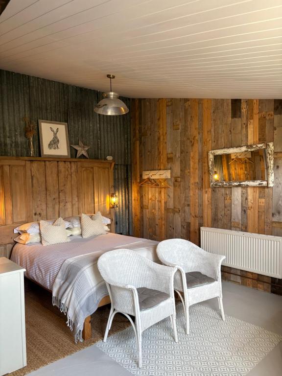 a bedroom with a bed with two chairs and wooden walls at The Pig and Sty in Hereford