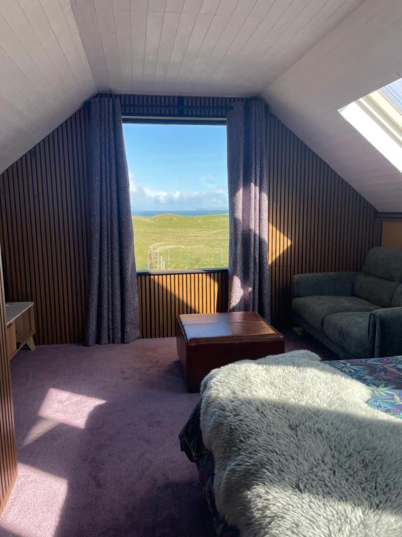a bedroom with a bed and a couch and a window at Seaside Suite Quilty in Quilty