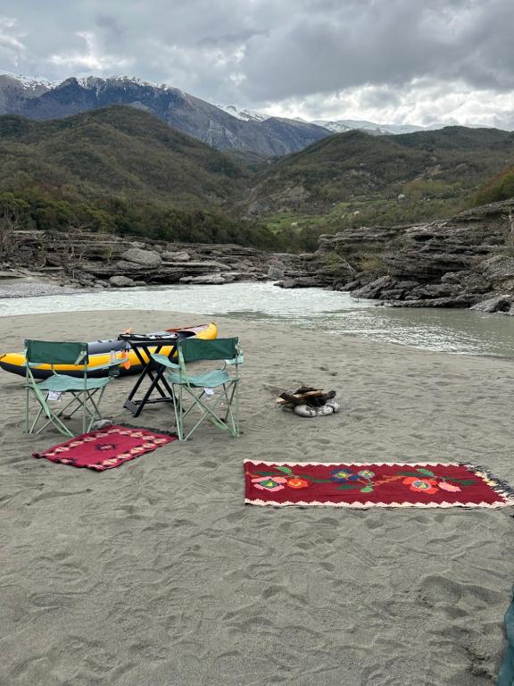 a beach with two chairs and a table and a dog at Wild Camping Vjosa in Përmet