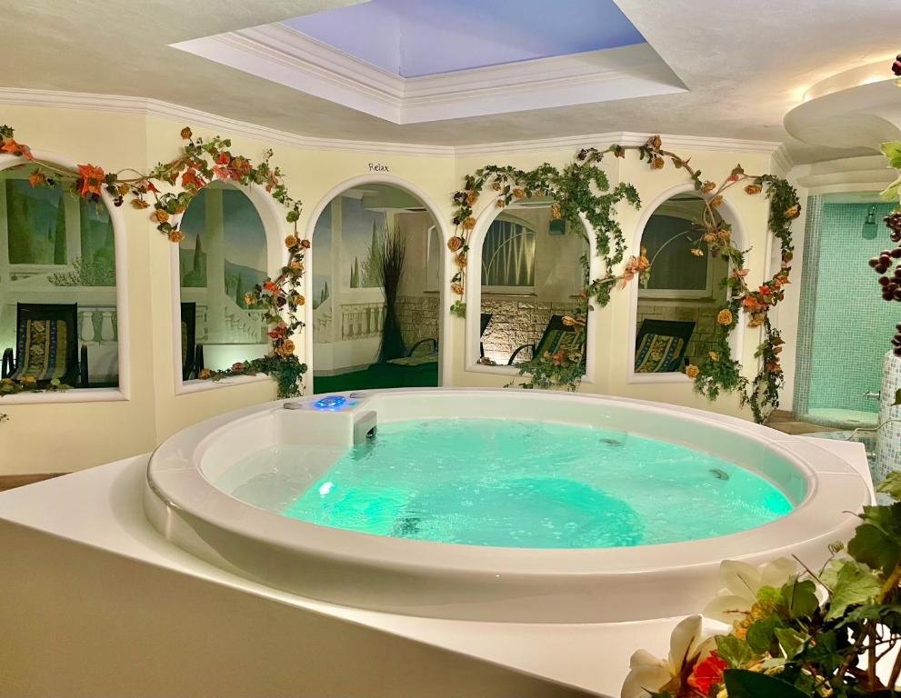 a large soaking tub in a room with mirrors at Hotel Waldheim in Sarnonico