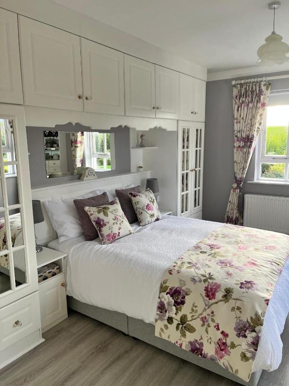 a bedroom with a large bed with white cabinets at Big Pop's House in Kilmacthomas