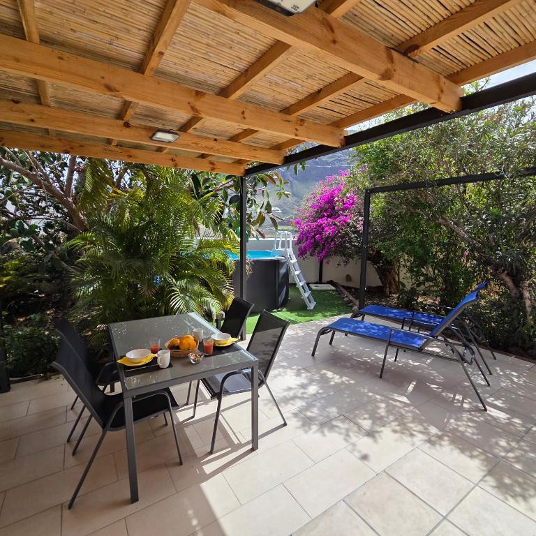 a patio with a table and chairs under a wooden roof at Casa Rural Anais in San Nicolás
