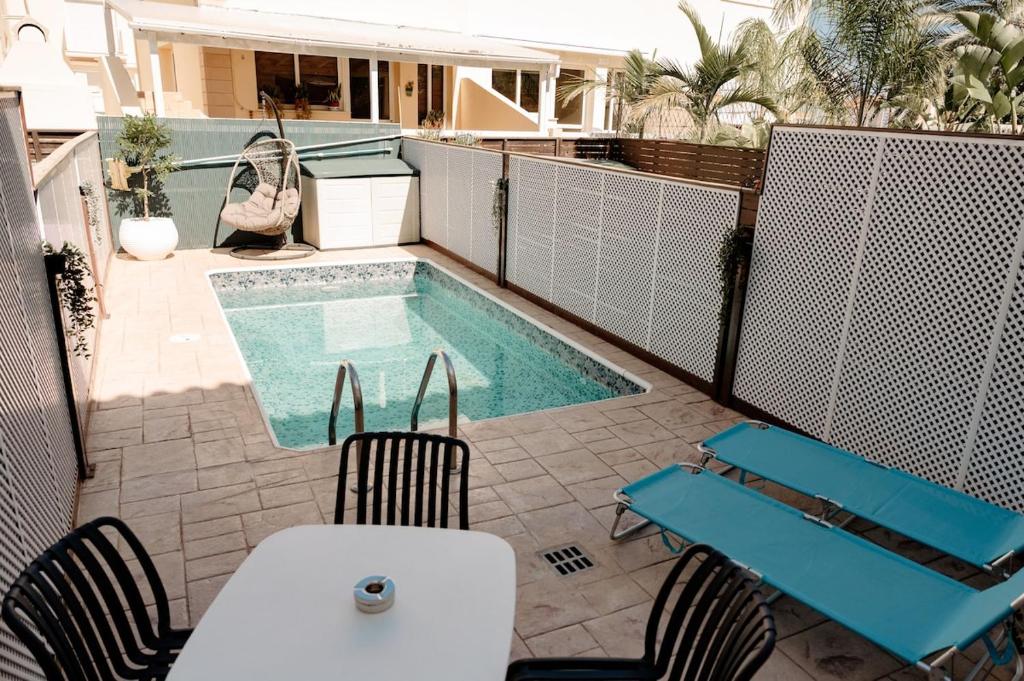 a patio with a pool and chairs and a table and a swimming pool at Toma Villa in Paralimni