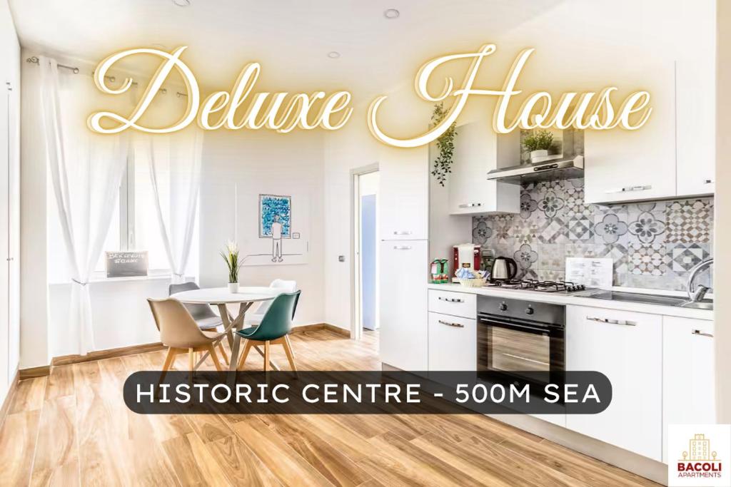 a kitchen with white cabinets and a table with chairs at Bacoli House Deluxe - Central & Elegant Design in Bacoli