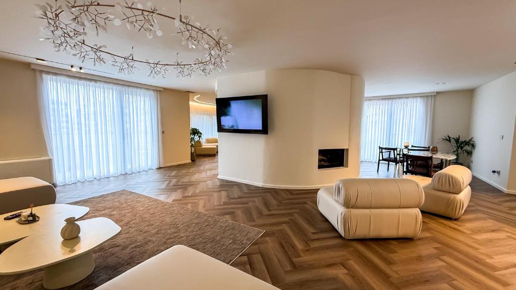 a living room with a couch and a tv on a wall at Vatër Selected Rooms in Tirana