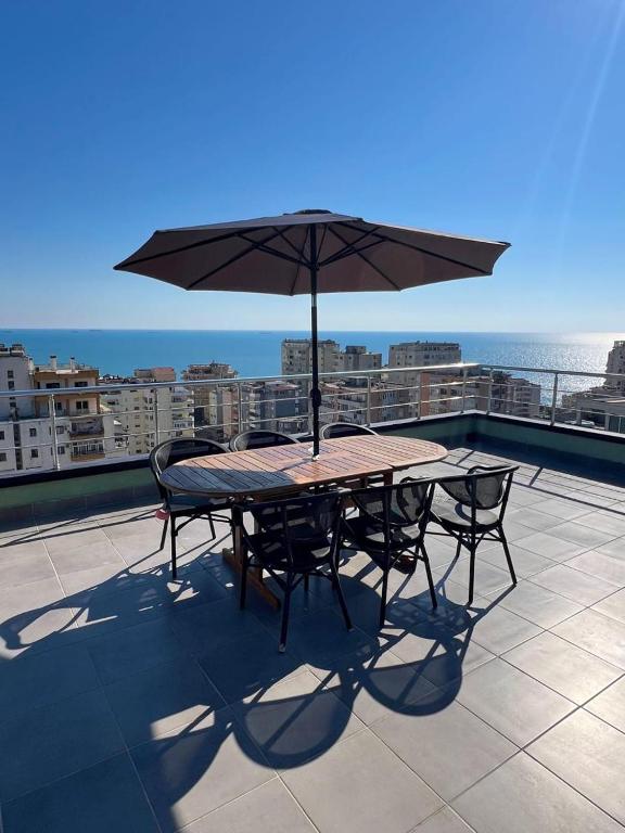 a table and chairs with an umbrella on a balcony at Sea View Penthouse in Durrës