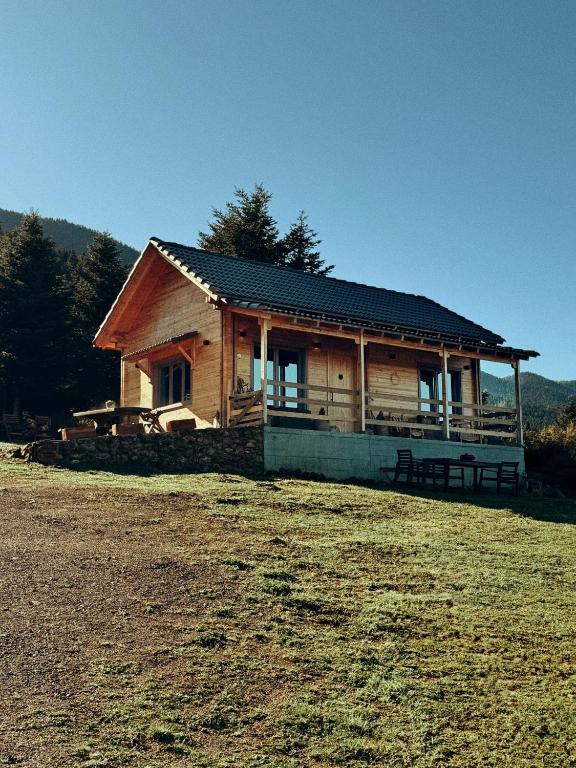 a small wooden cabin with a field in front of it at The Farmhouse in Vitina