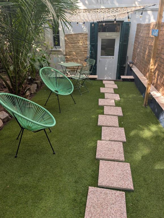 a patio with two green chairs and a pathway at Appartement Ajaccio in Ajaccio