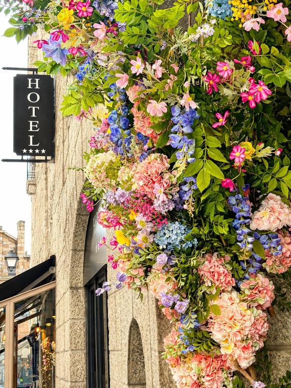 a bunch of flowers hanging from the side of a building at La Maison des Armateurs in Saint Malo