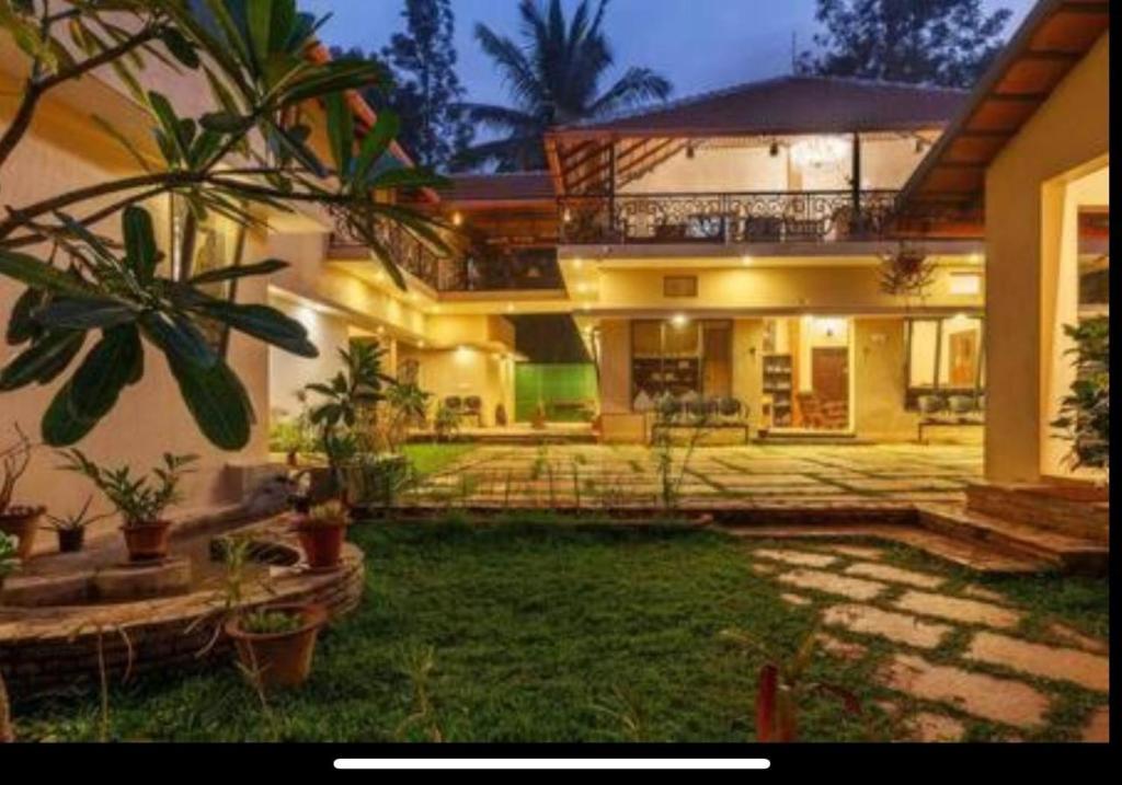 a large house with a yard with potted plants at Airyaman Hollistic Hive in Narasimharaja Puram