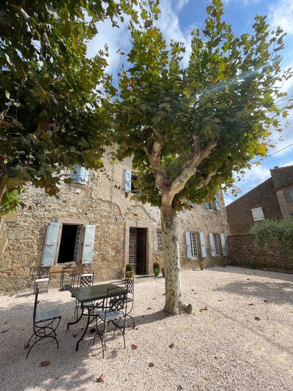 a table and chairs under a tree in front of a building at Les 3 Platanes in Conilhac-Corbières