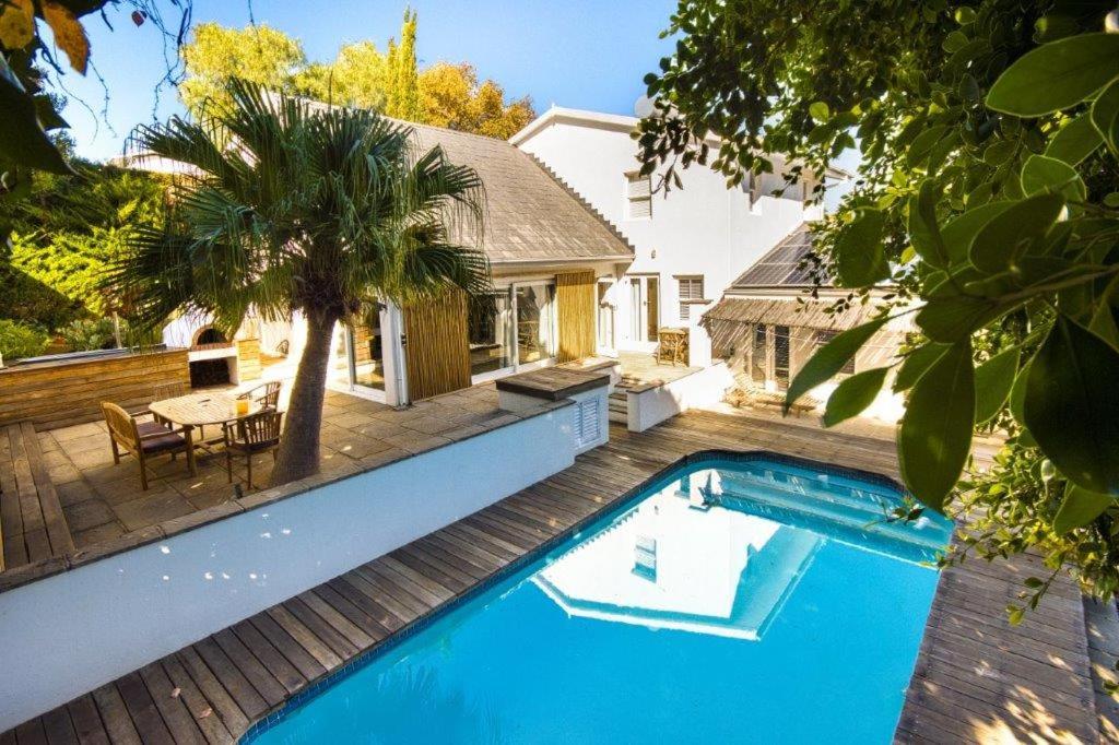 a large blue swimming pool on a deck with a house at Charming B&B in Somerset West