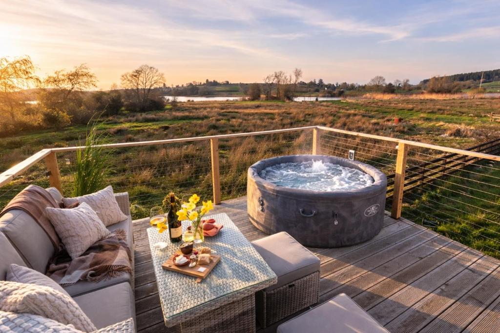 a hot tub on a deck with a couch and a table at Waterside Cabin in Belturbet