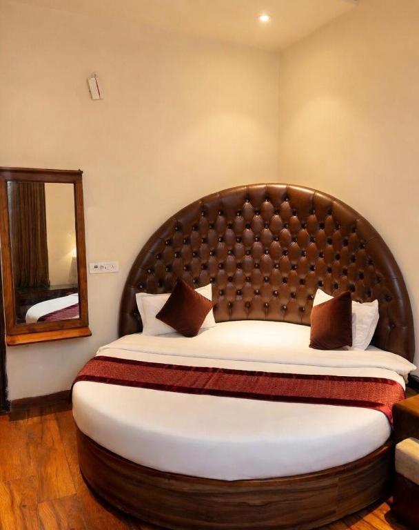 a bedroom with a large bed and a mirror at Hotel WoodCresstt Zirakpur !! Budget Friendly Stay With Airport Access in Zirakpur