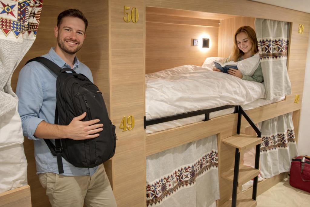 a man with a backpack standing next to a woman in a bunk bed at 12H Hostel in Al-ʿUla