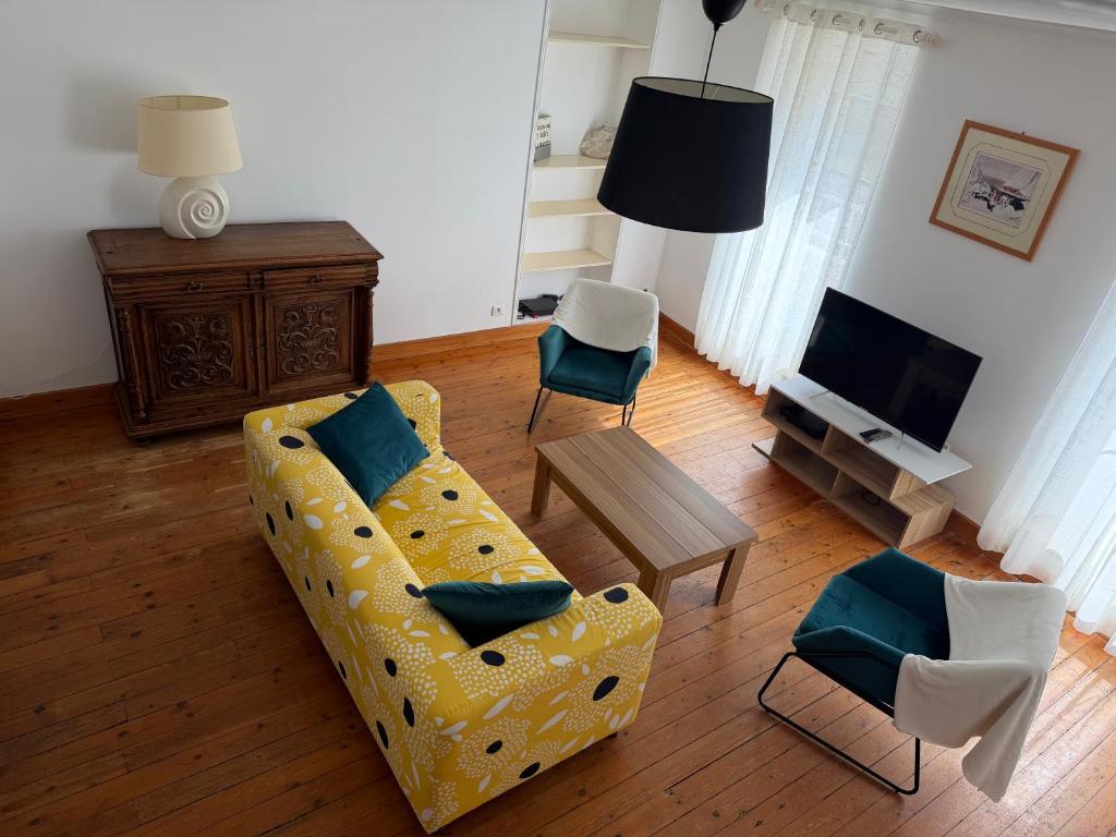 a living room with a yellow couch and chairs at L' Annexe Barneville Bourg in Barneville-Carteret