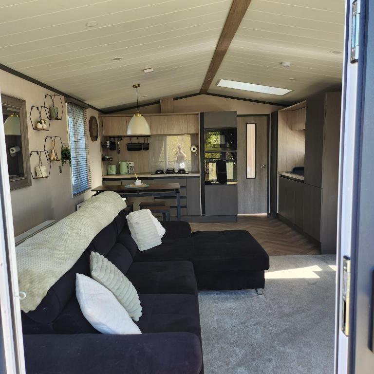 a living room with a black couch and a kitchen at 10 Sunset view in Scunthorpe