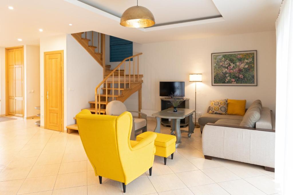 a living room with a yellow chair and a couch at AV villa in Nida