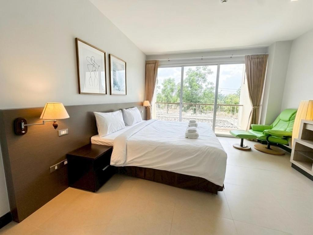 a bedroom with a large bed and a green chair at Satun Le Grand - โรงแรม สตูล เลอแกรนด์ in Ban To La Nua