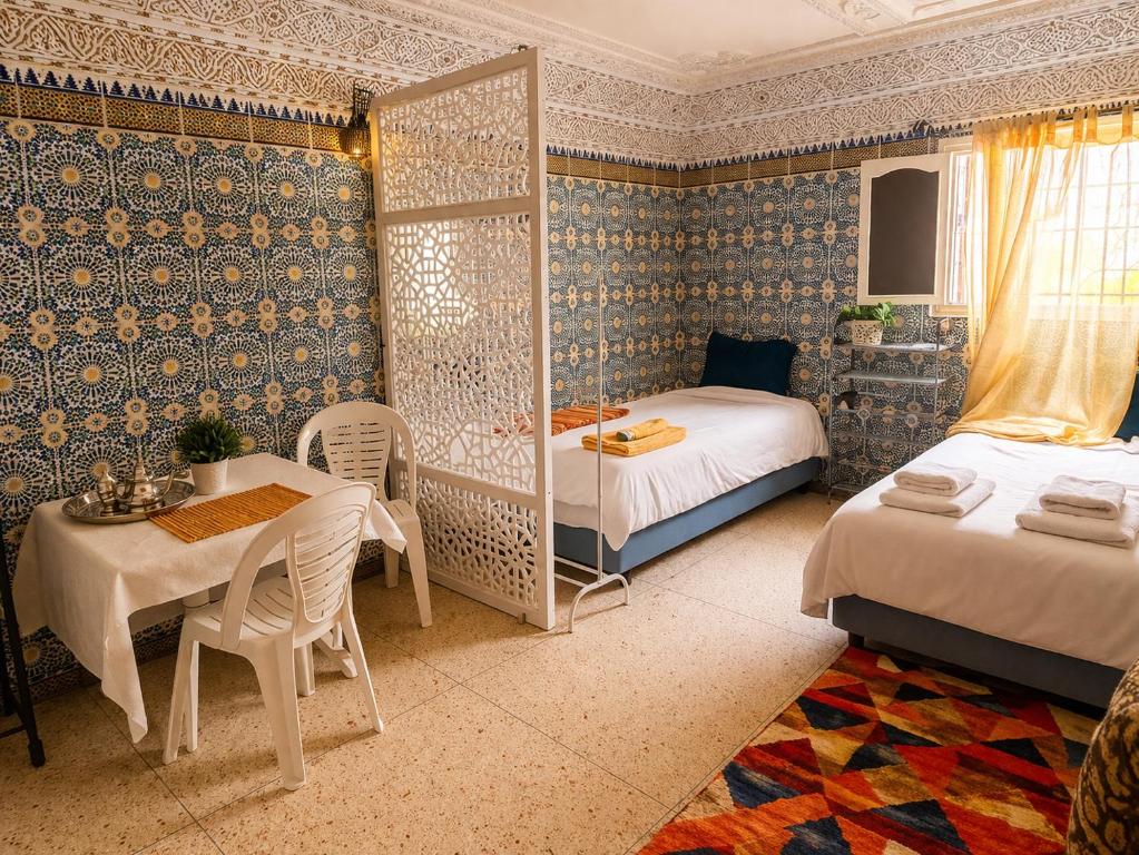 a bedroom with two beds and a table and a table and chairs at Ahmed house in Agadir