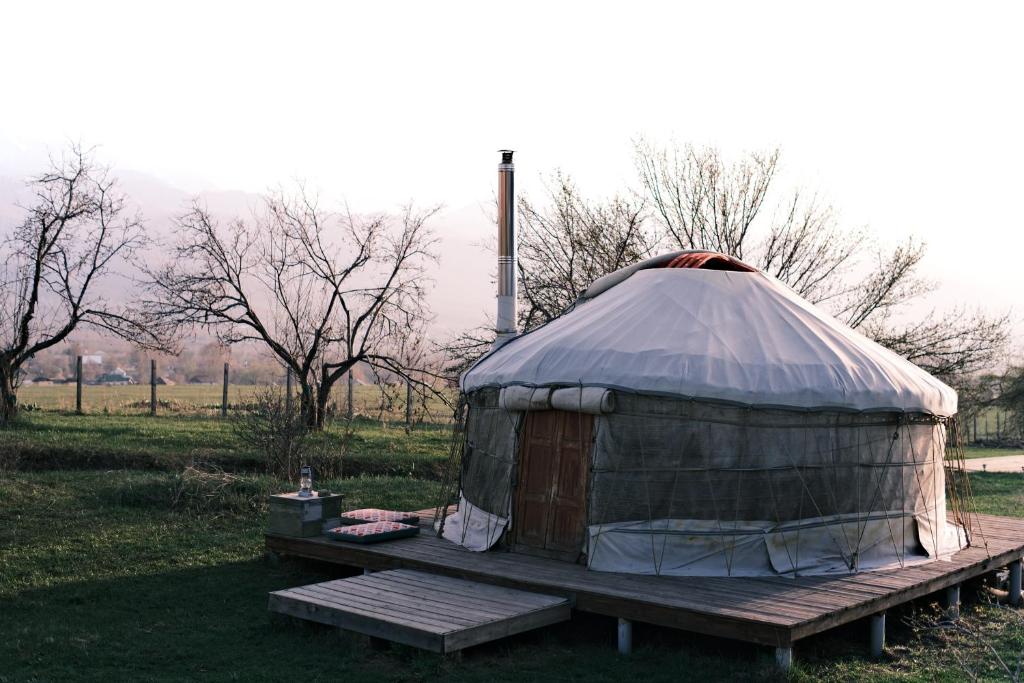 a yurt sitting on a wooden platform in a field at Nomad Yurt, 60 year old in Ryskulovo