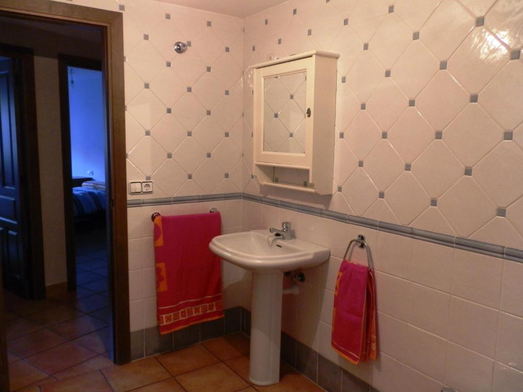y baño con lavabo, espejo y toallas rojas. en Apartamento Martín en Mora de Rubielos