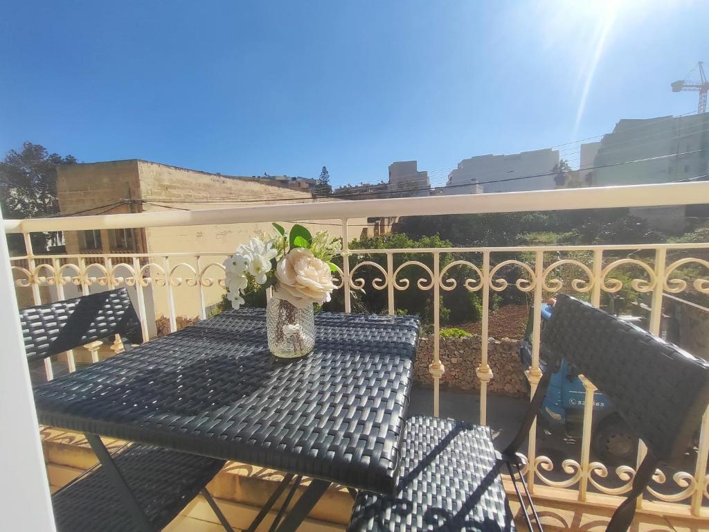 a table with a vase of flowers on a balcony at Ta'Roza Modern Apartment with Balcony & Distant Sea Views - Xaghra Gozo in Xagħra