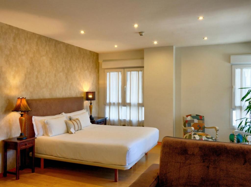 a bedroom with a white bed and a couch at Hospedaje Boutique Weber's in Gijón