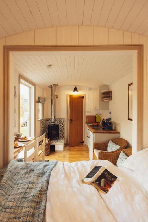 a bedroom with a large bed and a kitchen at Shepherd's Hut - Jasmine in Haverfordwest