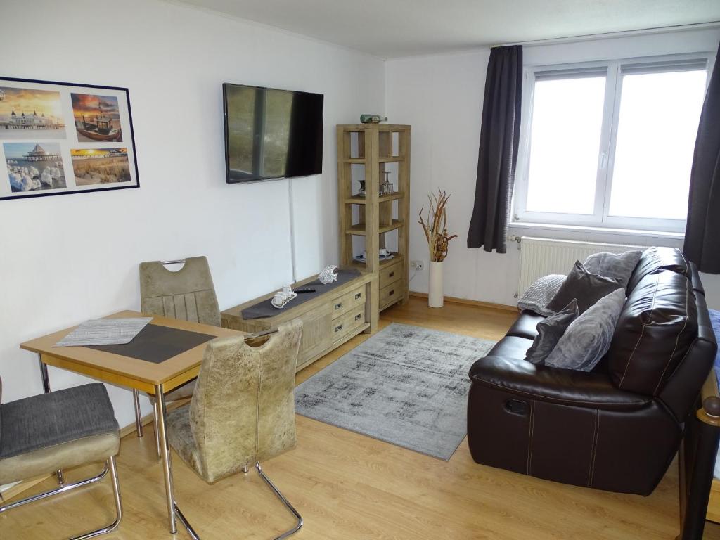 a living room with a leather chair and a table at DZ 11 Doppelzimmer in Heringsdorf