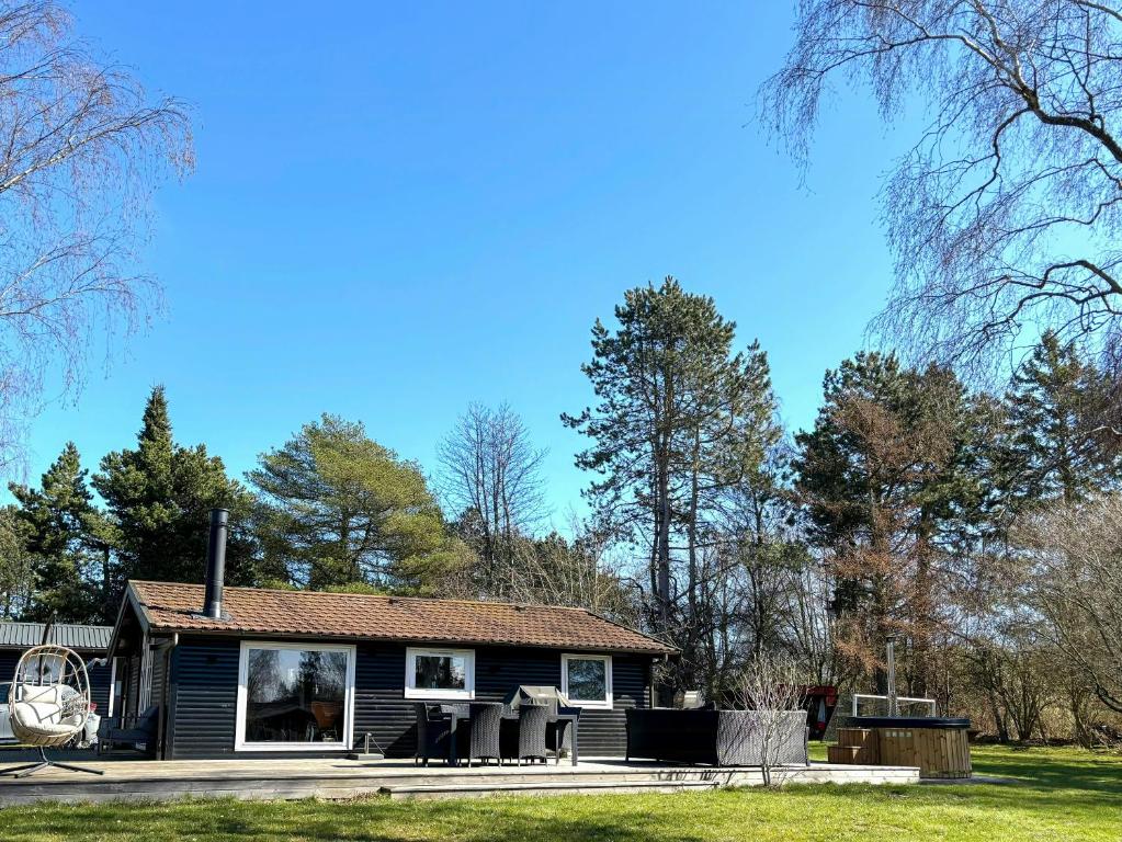 a small black house in a yard with trees at Summer House With Wilderness Bath By Kårup Forest in Fårevejle