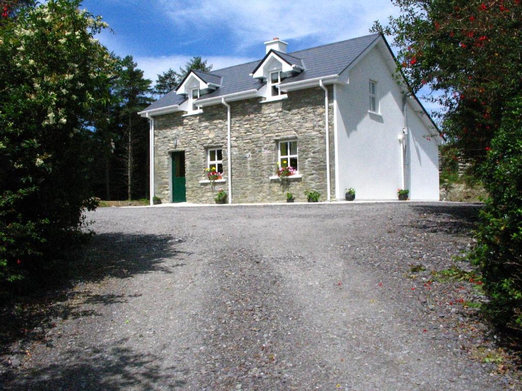 a stone house with a gravel driveway at Feirm Cottage in Kenmare