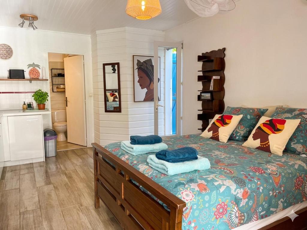 a bedroom with a bed with blue pillows on it at Studio accès piscine, plage à 50m in Le Gosier