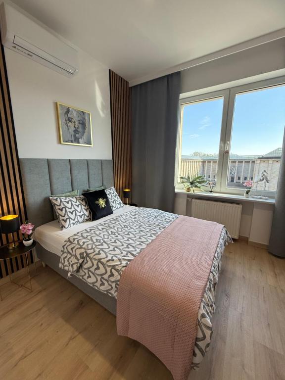 a bedroom with a bed and a large window at Exclusive Apartments Smolna in Warsaw