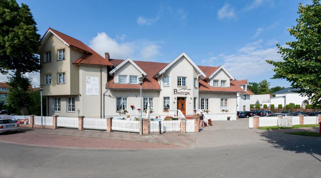 a building with a white fence in front of it at Bałtyk Resort in Rewal