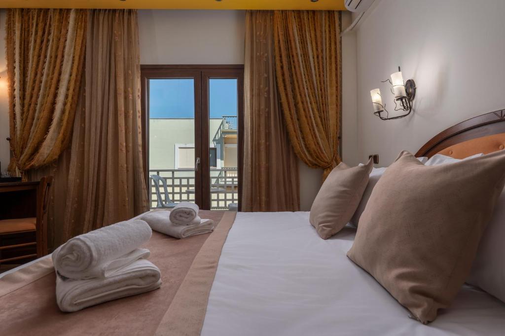 a bedroom with a large bed with towels on it at Filippos Hotel in Nea Moudania