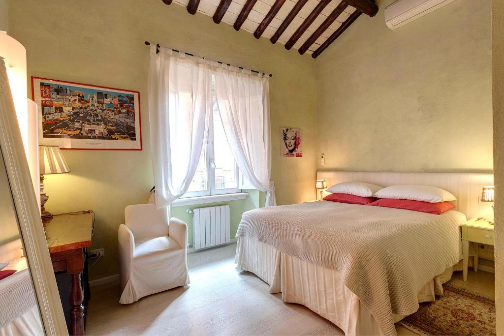 a bedroom with a bed and a chair and a window at LM Suites Spagna in Rome