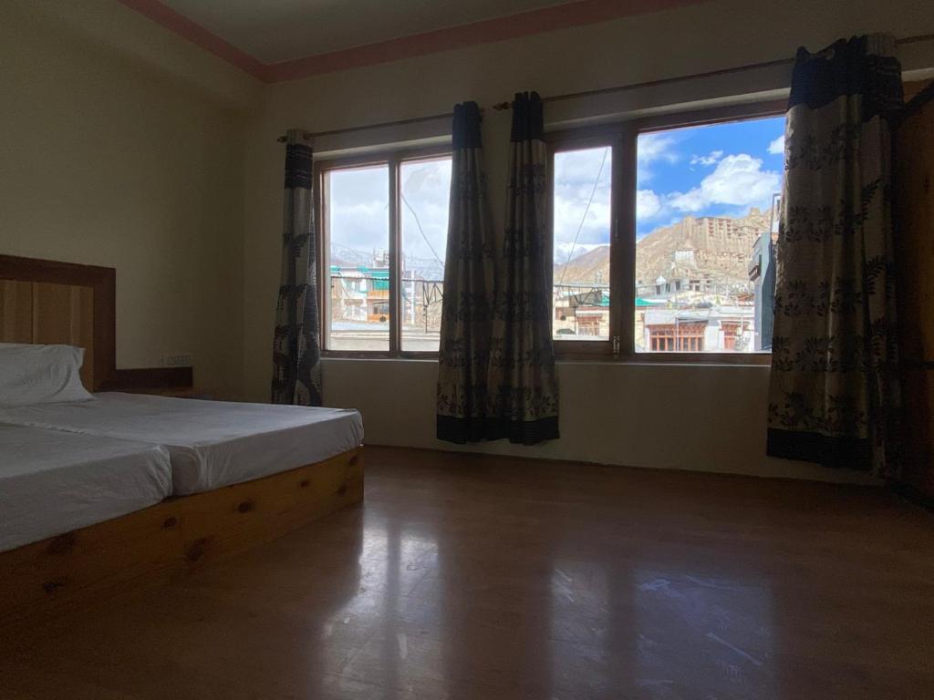 a bedroom with a bed and two large windows at Summer Villa in Leh