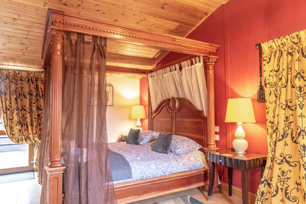 a bedroom with a canopy bed with red walls at Bouscat Lodge - Still Rabbit - Hot Tub - Yorkshire in Selby