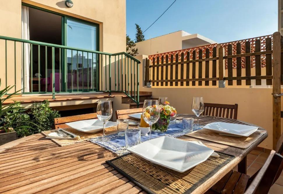 a wooden table with plates and wine glasses on a balcony at Apartamento Ca Na Fina, tranquilo y cerca de la playa de Es Pujols in Es Pujols