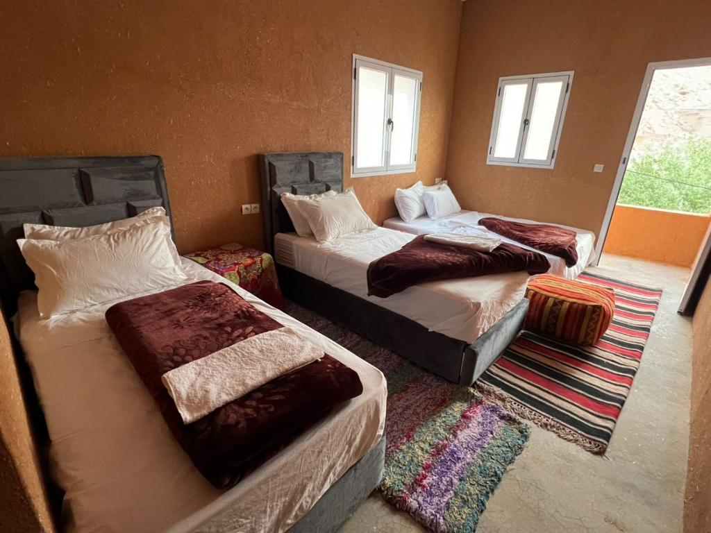 a bedroom with two beds and a room with windows at Pergolas Tamakouchte in Ouarzazate