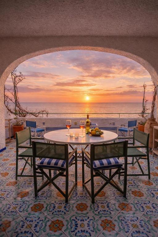 a table with wine glasses and a view of the ocean at Villetta La Conca in Conca dei Marini
