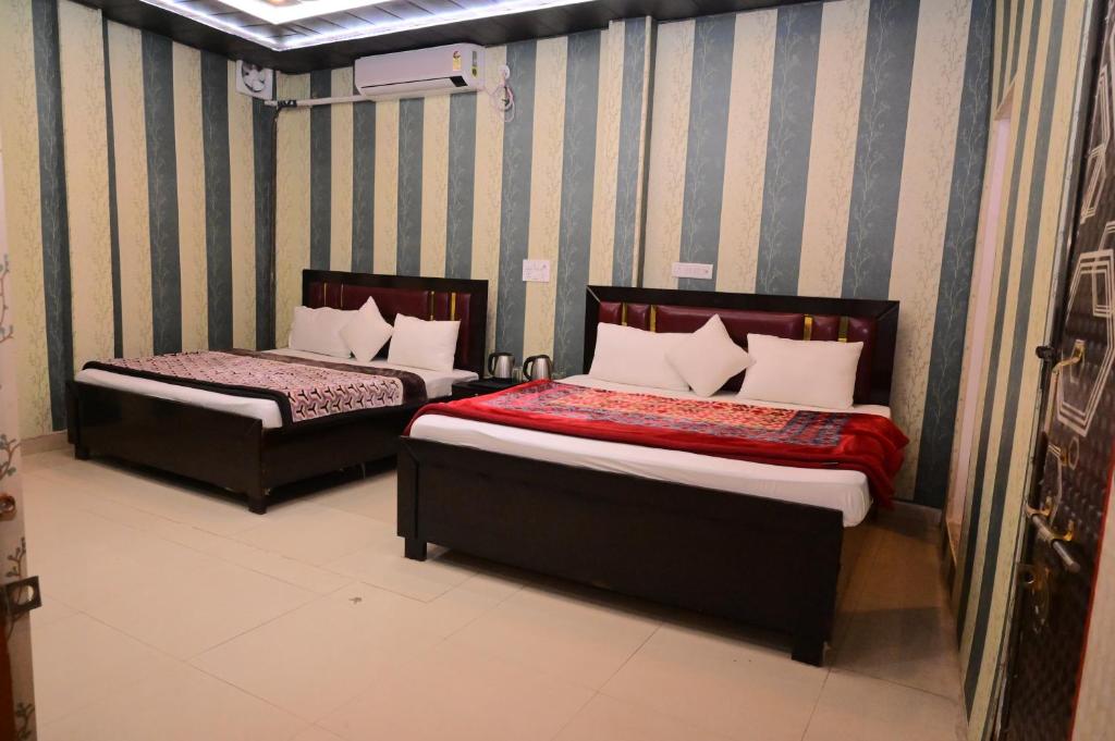 two beds in a room with striped walls at Swastik homestay ayodhya in Ayodhya