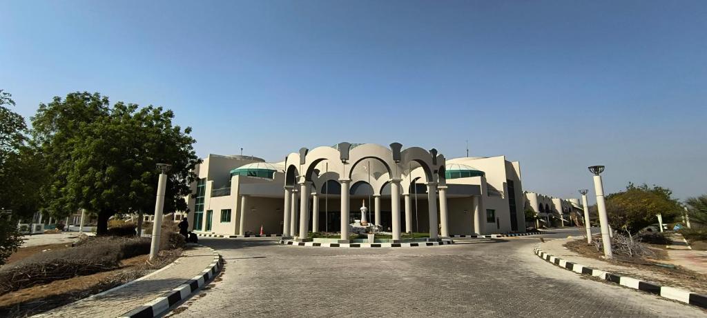 a large building with a road in front of it at Arabian Palace Hotel in Al Rahba